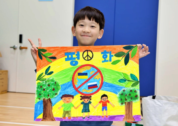 지난해 개최한 ‘제6회 평화사랑 그림그리기 국제대회’에서 이스라엘-하마스 전쟁으로 고통받는 친구들의 사진을 보며 평화가 오기를 간절히 바라는 마음으로 그림과 함께 기념사진을 찍고 있다.(사진=IWPG 익산지부)