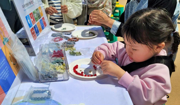 지난 26일 제6주년 ’4.26 세계여성평화의 날’에 가족들과 서동공원을 찾은 어린이는 평화를 간절히 바라는 마음으로 고사리 같은 손으로 소원팔찌를 만드는데 집중하고 있다. (사진=유유례 기자)